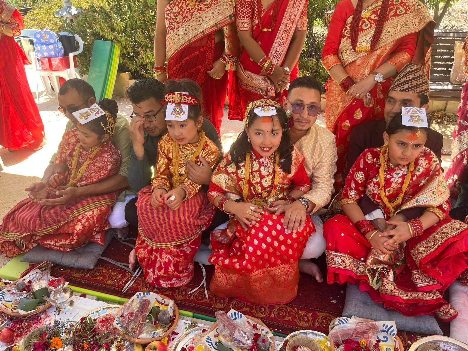 Families in ceremonial dress seated together at an outdoor gathering
